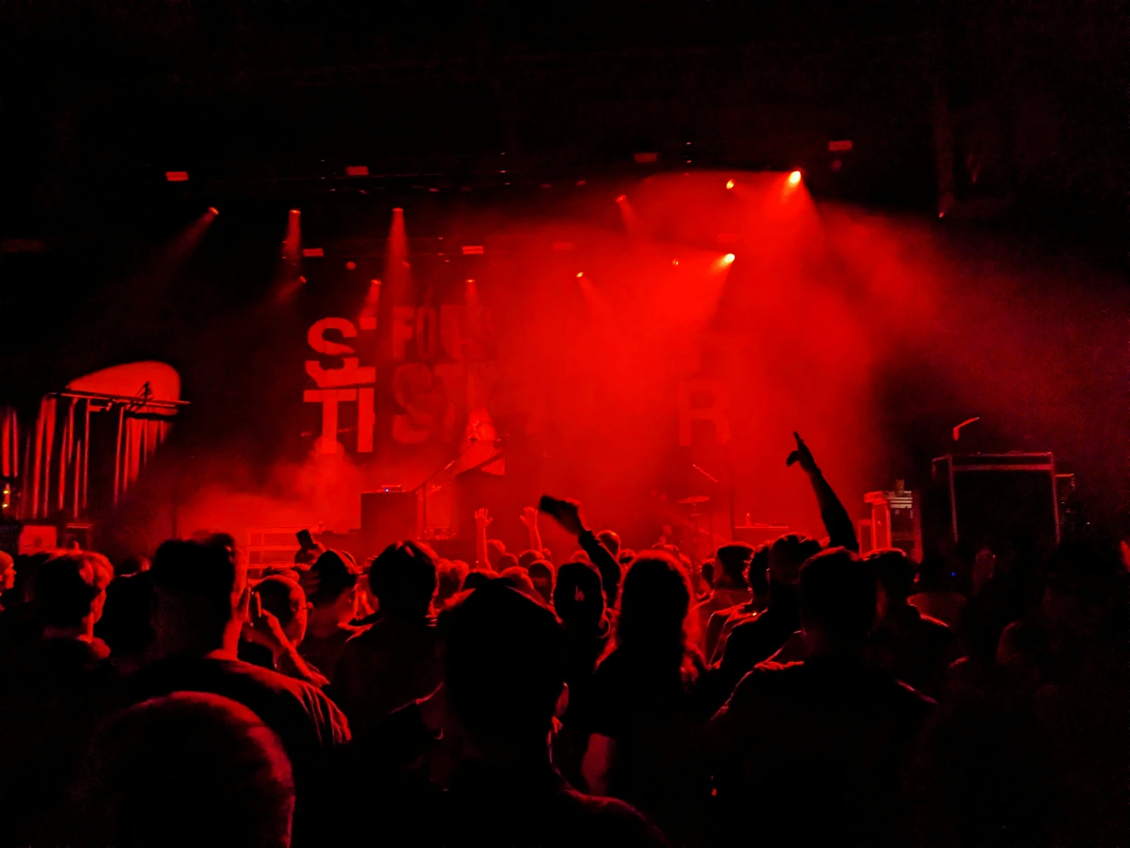 Concert crowd facing a stage with red lights